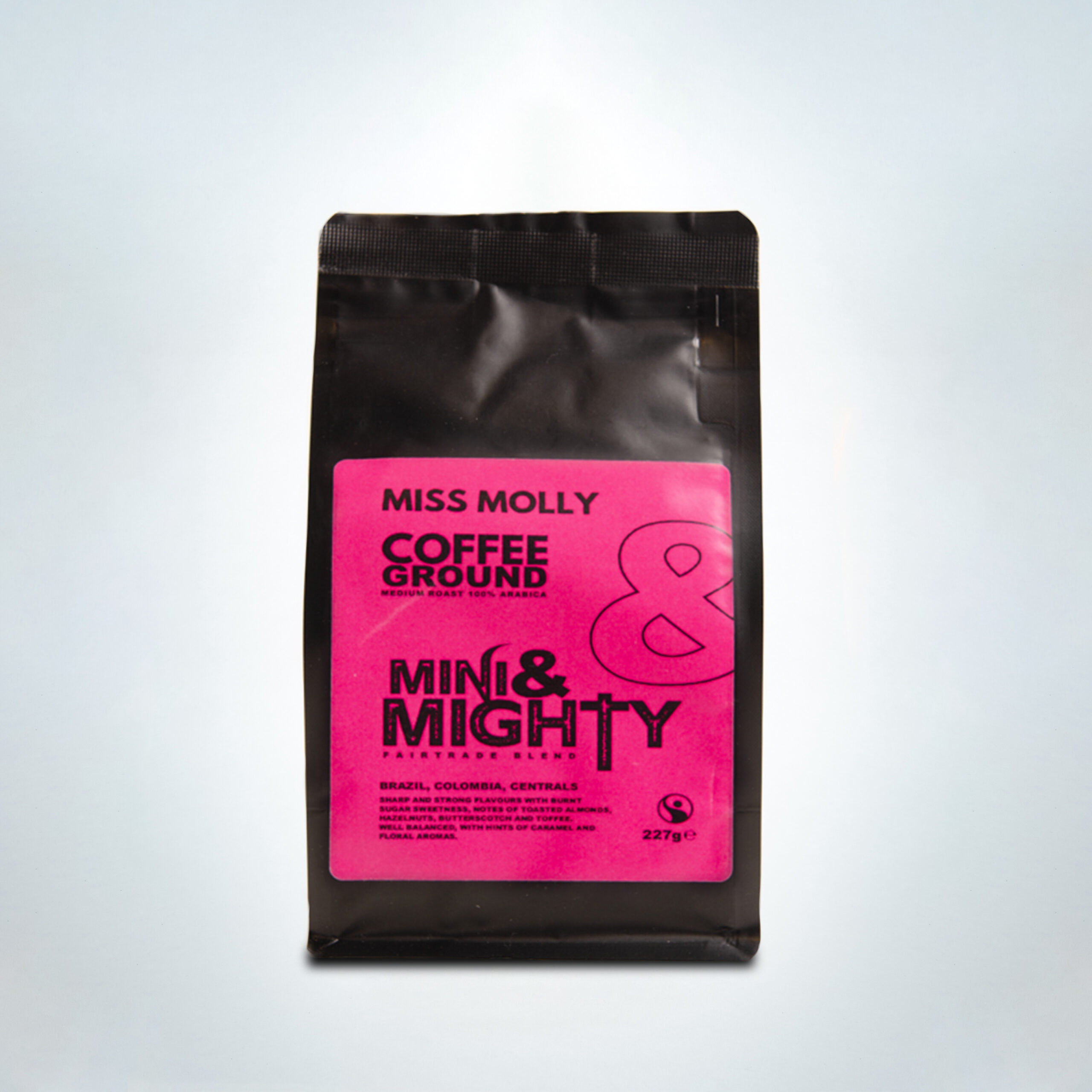 227g bag of Mini & Mighty “Miss Molly” ground coffee with a vibrant pink label. A medium roast Fairtrade blend of 100% Arabica beans from Brazil, Colombia, and Central America, featuring strong flavours of burnt sugar, toasted nuts, butterscotch, and hints of caramel and floral aroma.