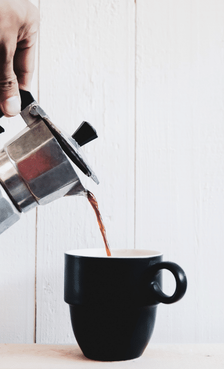 Moka pot brewing on a stovetop from Mini & Mighty Espresso, showcasing its classic aluminum design with a black handle and knob, capturing the traditional Italian method of making rich, espresso-like coffee.