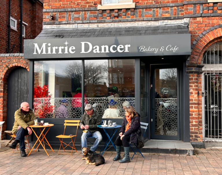 Mirrie Dancer Bakery & Café with outdoor seating and customers enjoying coffee — a charming spot proudly serving Mini & Mighty Coffee.