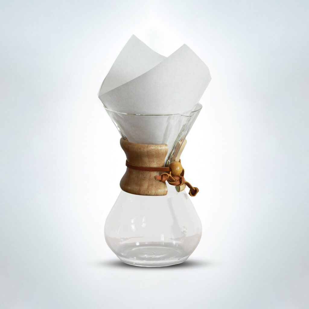 Chemex pour-over coffee maker with paper filter, featuring a wooden collar and leather tie, set against a light background
