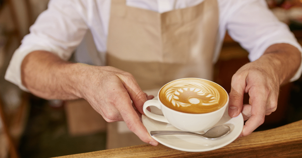 Cup of freshly served coffee being placed on a serving surface, showing freshly brewed coffee inside the cup ready to drink.